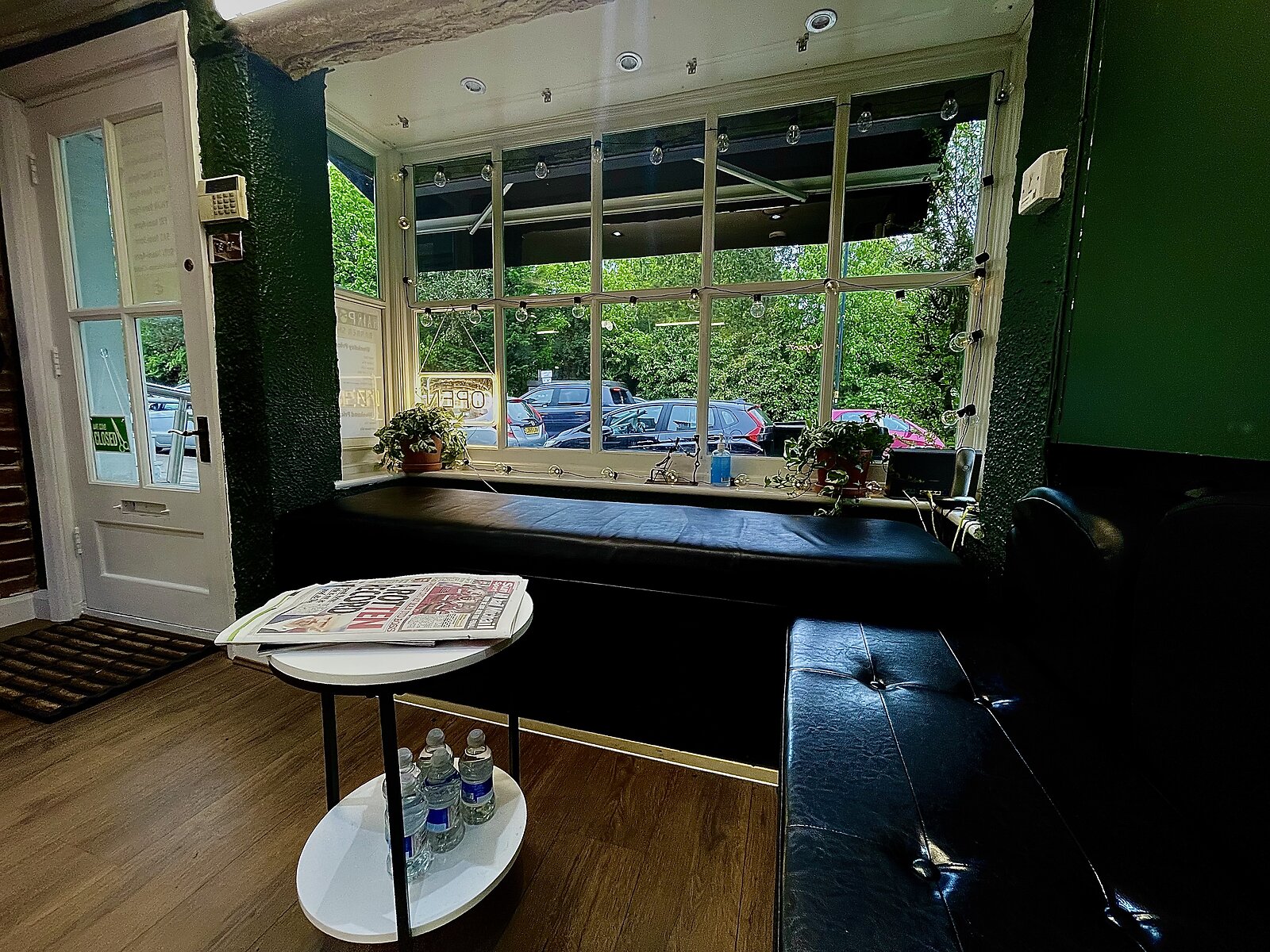 Waiting area at Hairport Barber Shop with bench seating and newspapers