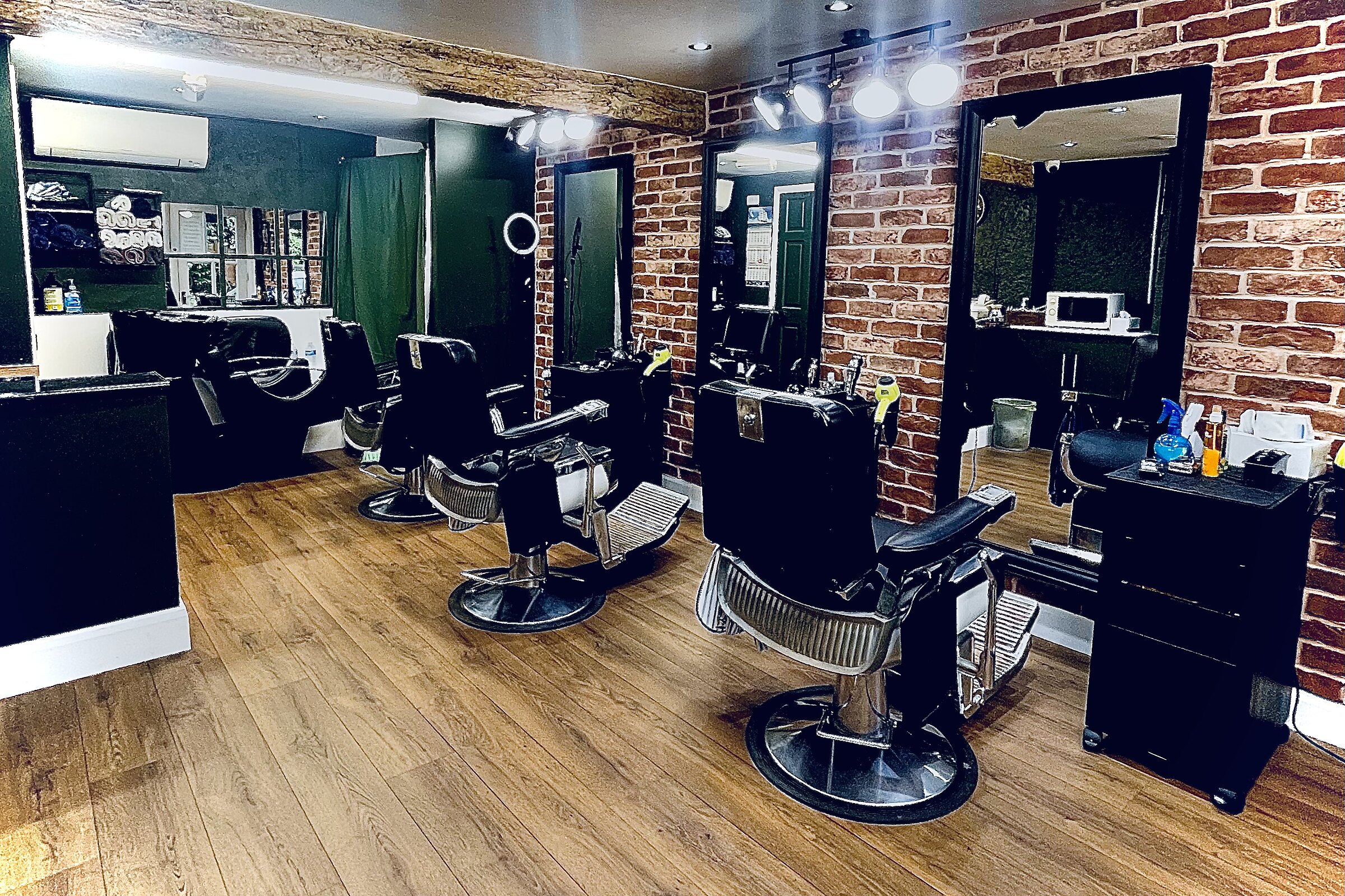 Interior of Hairport Barber Shop showing three traditional barber chairs against an exposed brick wall